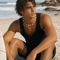 May include: A beaded necklace featuring a repeating pattern of small white and black cylindrical beads. The necklace is worn around the neck, resting against the collarbone, and consists of uniform, smooth beads strung together in a simple, circular design.