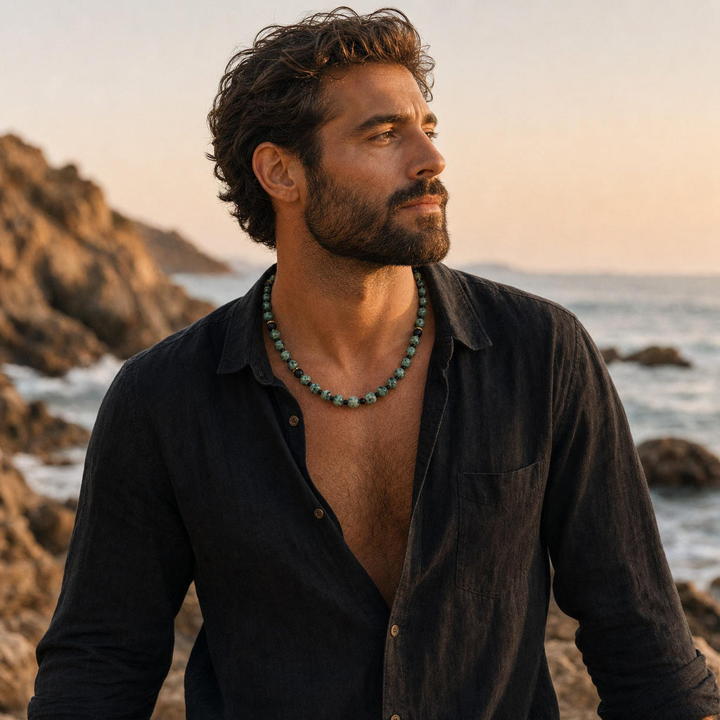 May include: A beaded necklace featuring alternating round turquoise-colored stone beads with dark brown or black accents, worn around the neck. The necklace consists of a single strand of polished spherical beads that sit against the skin.