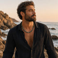 May include: A beaded necklace featuring alternating round turquoise-colored stone beads with dark brown or black accents, worn around the neck. The necklace consists of a single strand of polished spherical beads that sit against the skin.