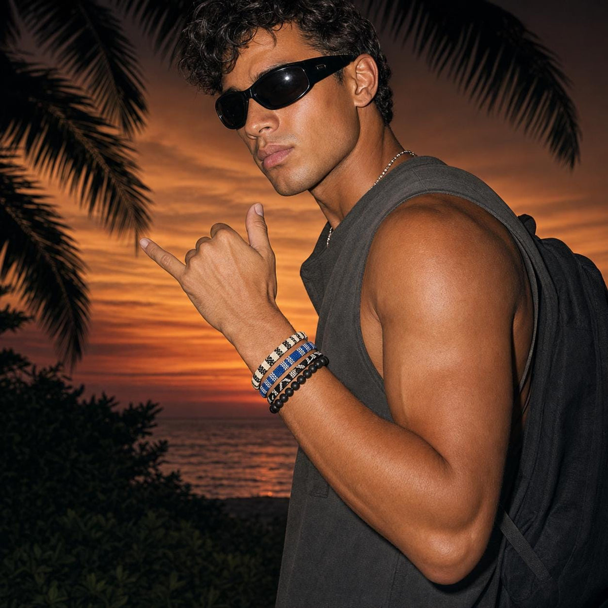 May include: A set of four bracelets worn on the wrist, featuring three woven bands with geometric patterns in black, white, and blue, alongside one bracelet composed of smooth, matte black spherical beads. The bracelets are worn together.